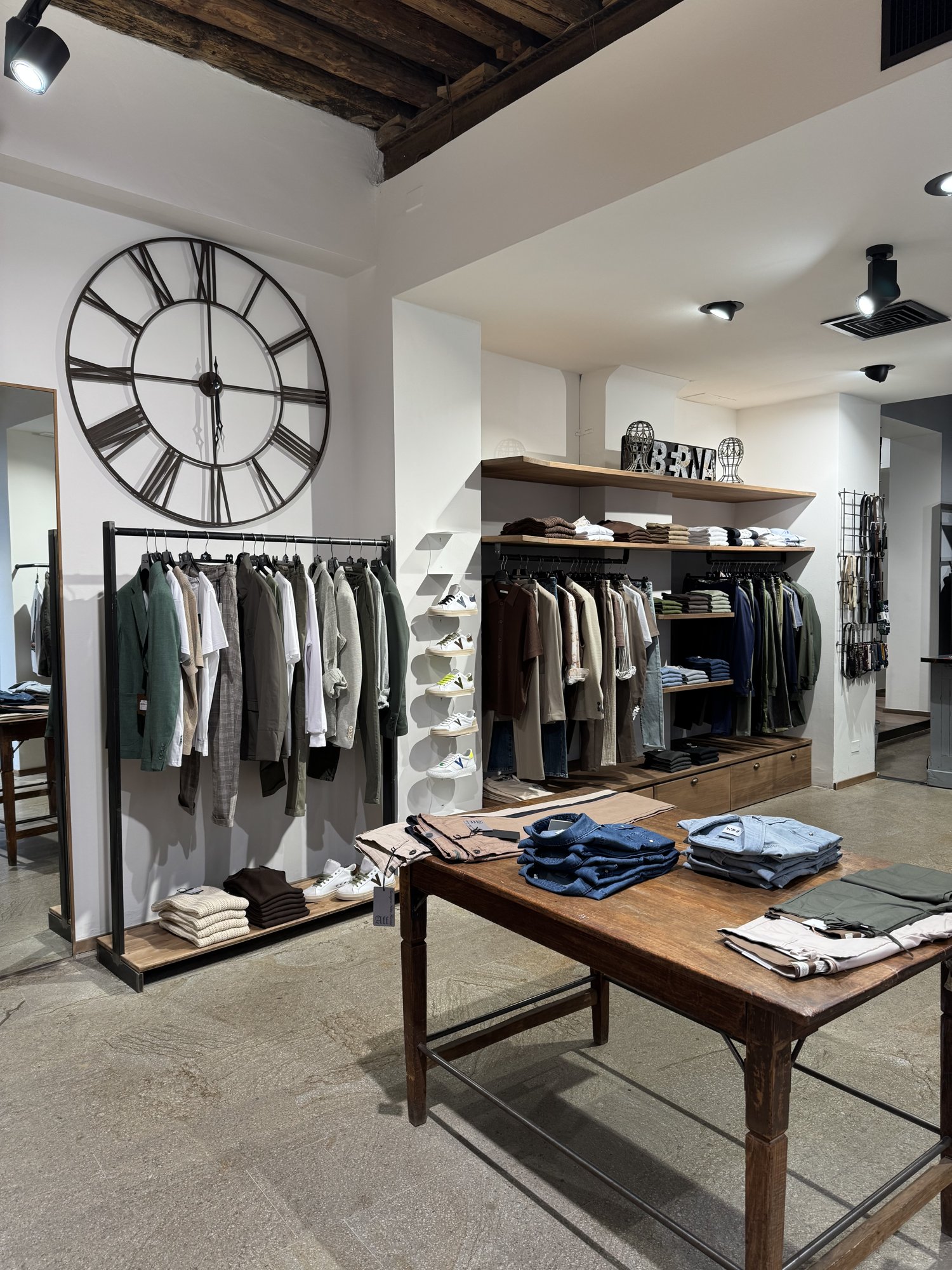 Interno Box Uomo Padova con grande orologio e tavolo in legno